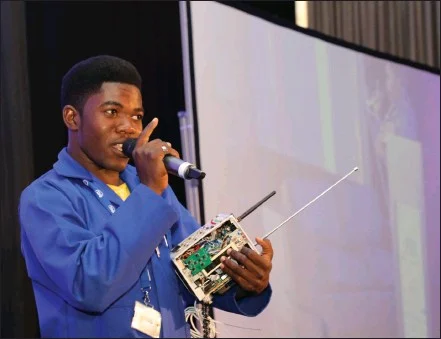 Simon Petrus explaining the functionalities of his SIM-free phone, highlighting its potential impact on communication in areas with limited infrastructure.