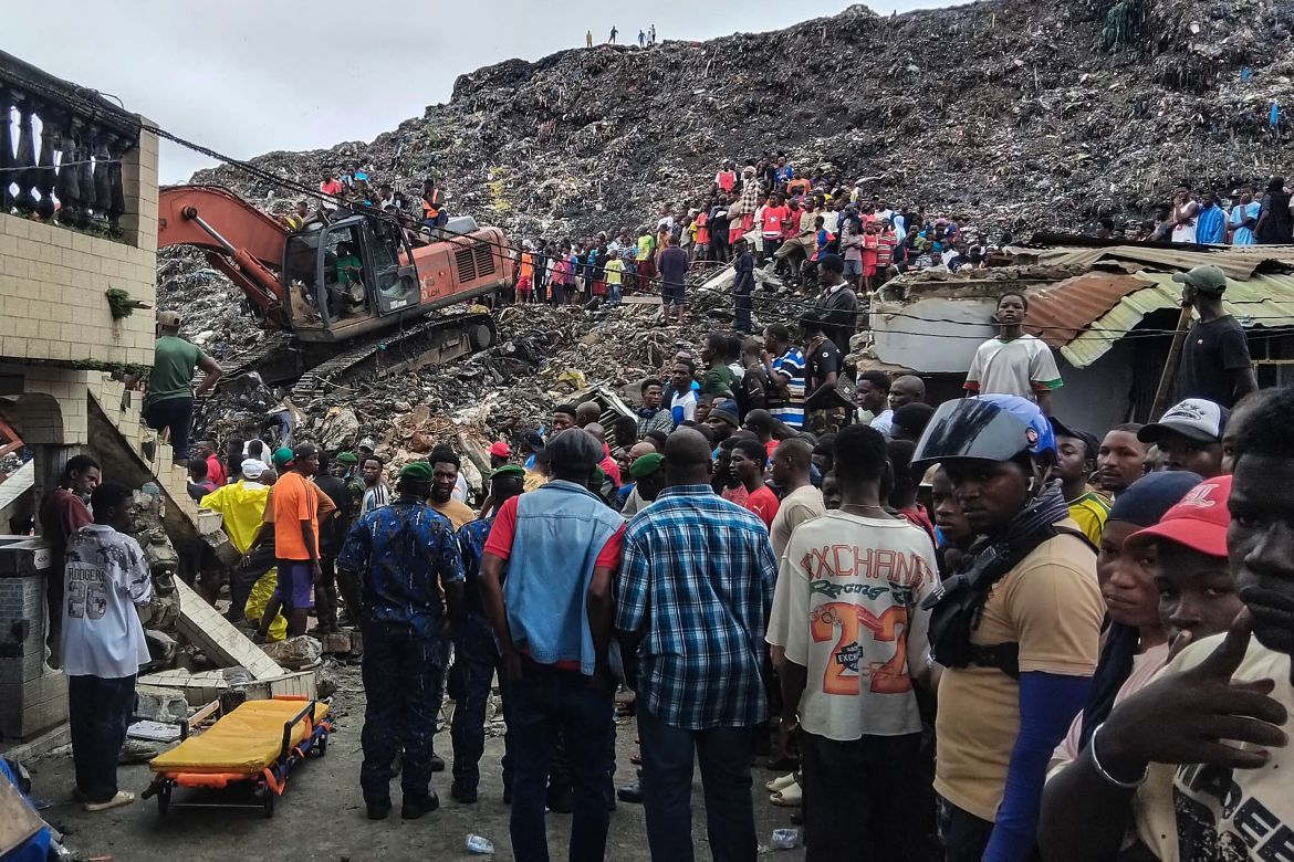 A caterpillar digs through the mountain of rubble, slowly clearing the debris in a desperate search to recover bodies trapped beneath the ruins.