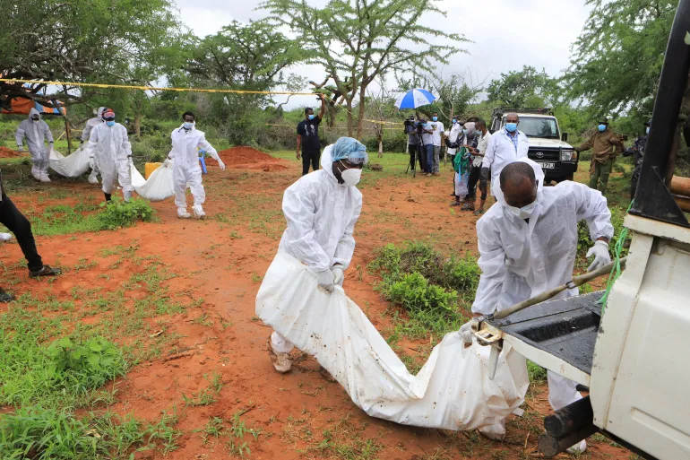 Forensic experts and homicide detectives carry the bodies of suspected members of a Christian cult exhumed from graves in Shakahola Forest in Kenya
